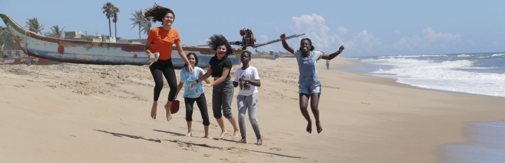 Students jumping up in the air on a beach.