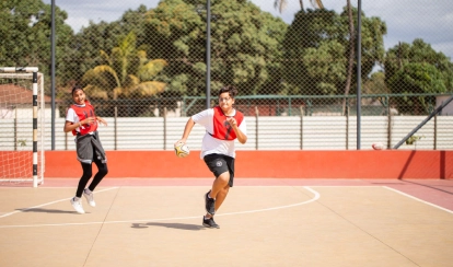 A group of students at AKA Dhaka sit around a table in the art studio, painting vibrant artworks on canvas with brushes and pastels.