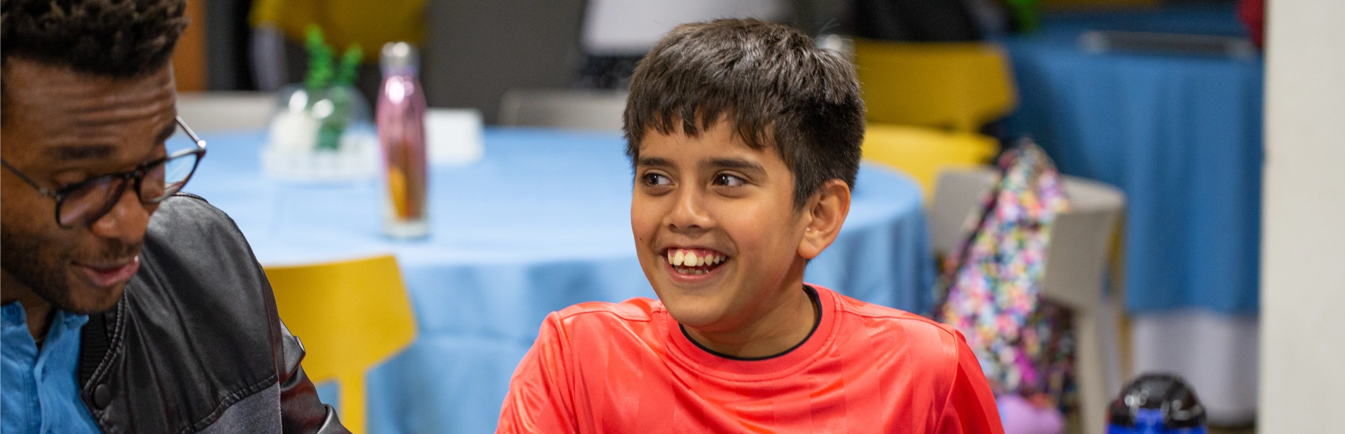 : A student and teacher sit together at a table during dinnertime.