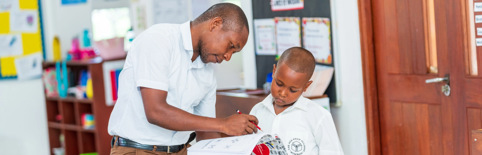 A Junior School student and teacher looking at a book together.