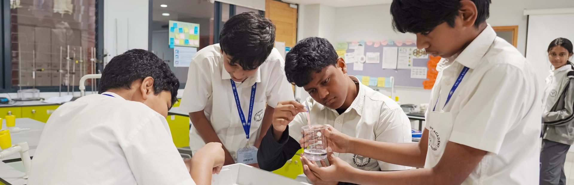 Students and a teacher conduct a science experiment using lab equipment in a classroom.