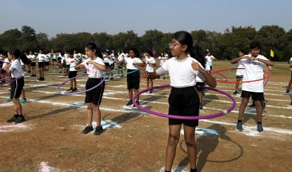 A group of Junior School students dressed in white taekwondo uniforms perform coordinated moves on a green mat during the Annual Sports Day on the school field.