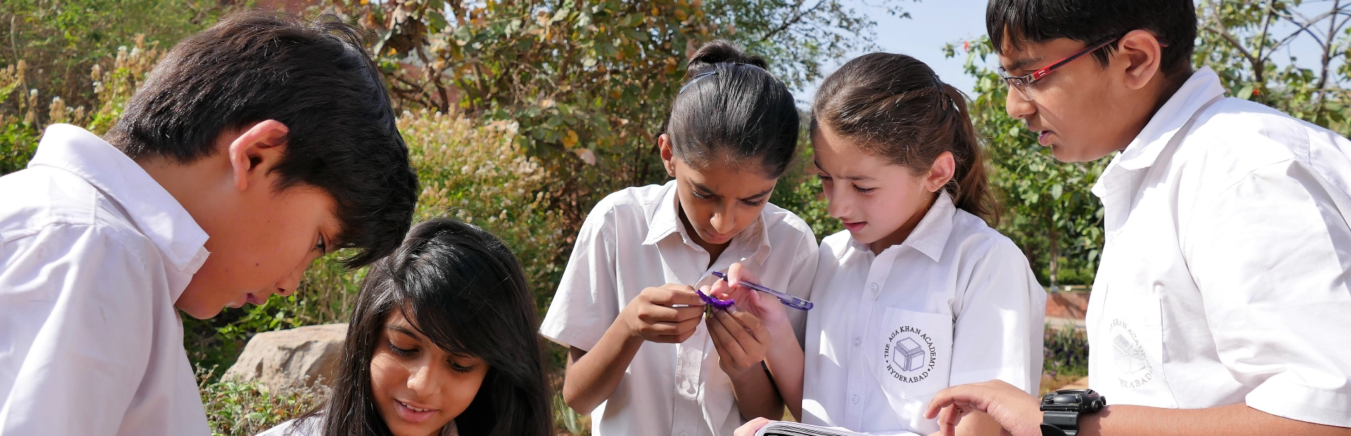 Four students from AKA Hyderabad stand outside together while working on an activity. 