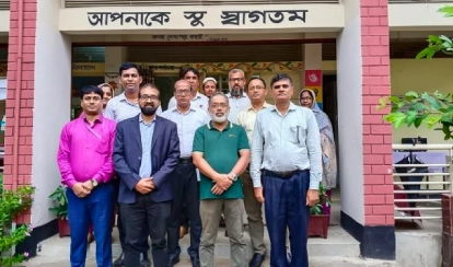 A group of educators and professionals stand in front of a government primary school during a PDC field visit for the KIX project observation.