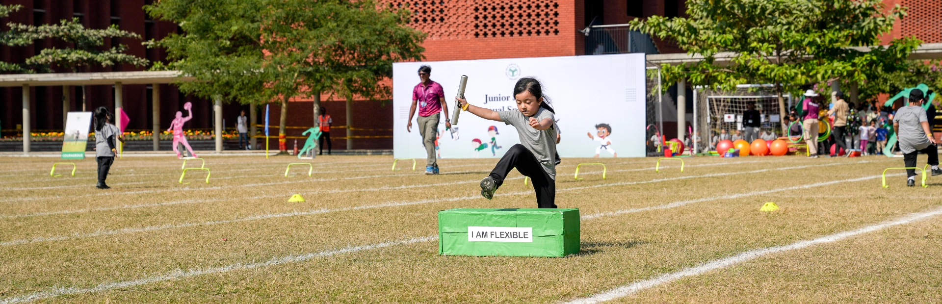 A student jumps over a hurdle on a field.